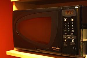 A small, counter-top microwave oven is shown. Microwave ovens use electromagnetic waves to heat food.