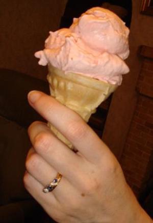 A woman holds a strawberry ice cream cone.