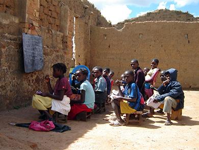 This is an image of children sitting in a ruined structure which serves as their outdoor 'classroom.'
