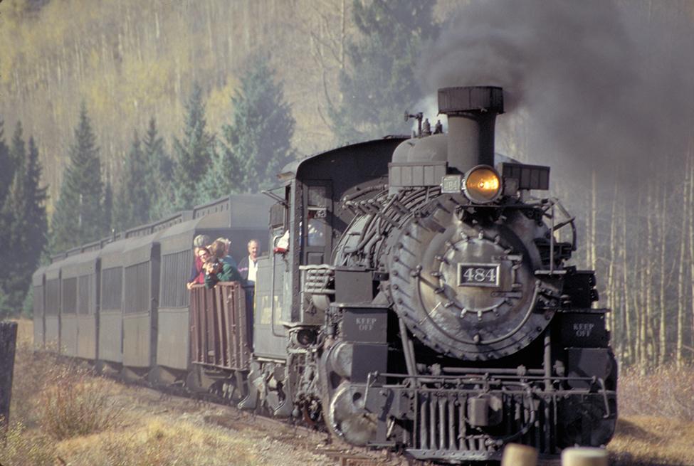 Smoke rises from the stack of a train travelling through the mountains