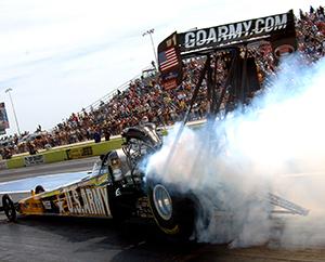 Smoke is coming from the tires of a race car as the car accelerates at the beginning of a drag race.