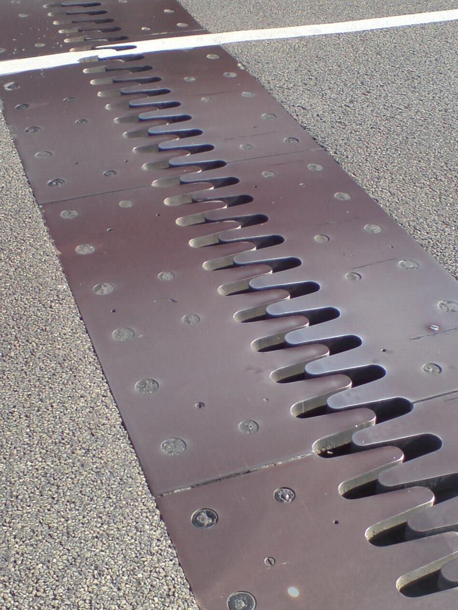 A picture of a thermal expansion joint is shown. It is metal attached to concrete. The metal has interlocking teeth that allow the surface to expand.