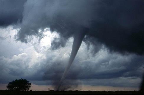 The figure shows a photograph of a dark tornado funnel cloud touching the ground and kicking up a lot of debris.