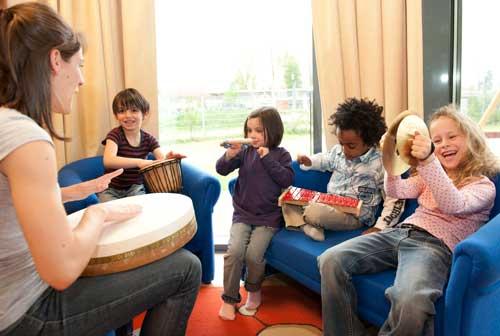 Image of students sitting in front of teacher with guitar