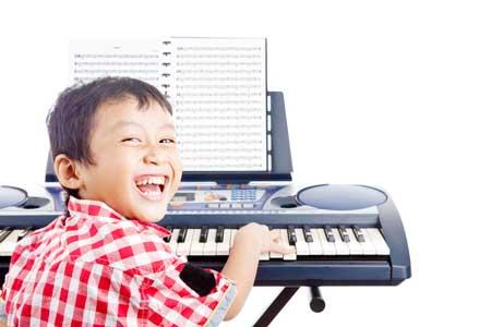 Image of boy playing the keyboard with sheet music in front of him