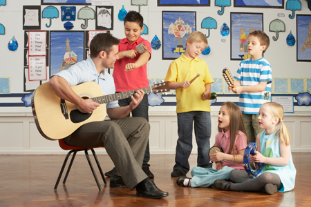 Image teacher with guitar in front of elementary students with instruments