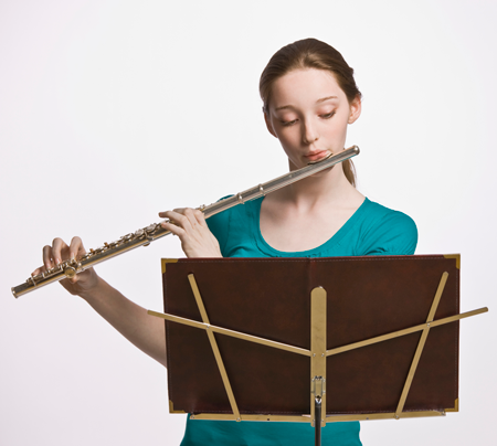 Image of a student playing the flute and reading music from a music stand