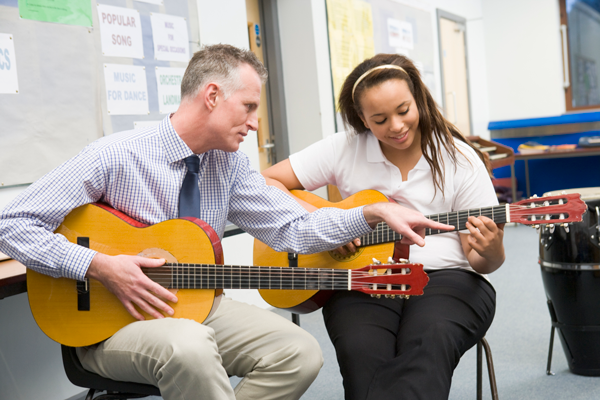 Image of teacher and student playing guitar