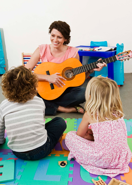 Image of students sitting in front of teacher with guitar