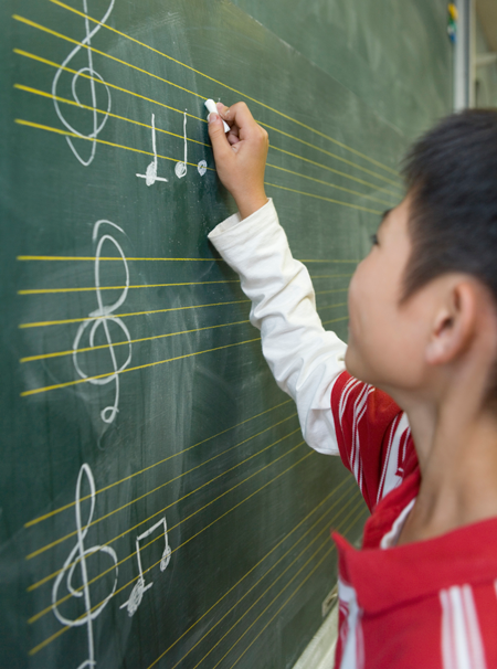 Image of student writing music on a chalkboard