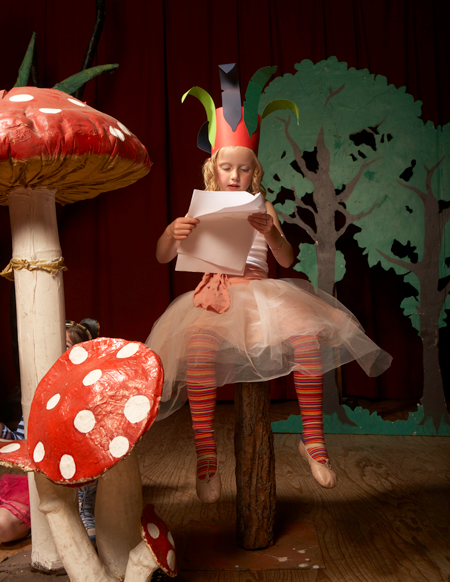 Image of girl reading a script in costume on stage