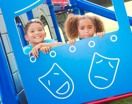 Image of a young boy and girl behind a small theatre set