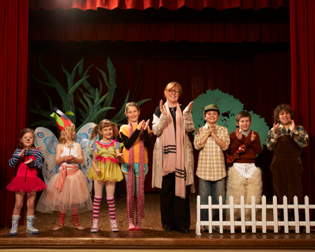Image of elementary students and teacher on stage in front of set