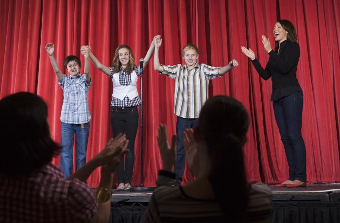 Three children preparing to take a bow on stage