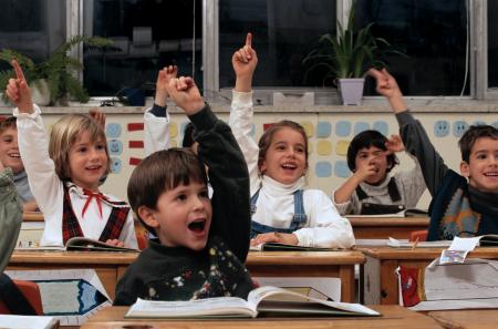 children raising their hands in a classroom