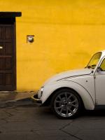 Volkswagen Beetle parked in front of a yellow building.